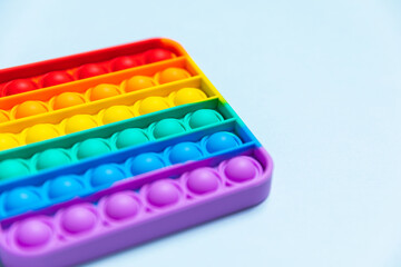 Push Bubble Fidget Toy Pop It on blue background. Trendy rainbow anti-stress sensory toy popit for popping bubbles. Copy space, Close up