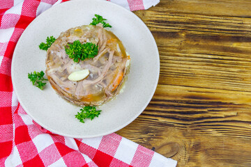 Meat aspic in a plate on a wooden table. Top view. Traditional russian dish