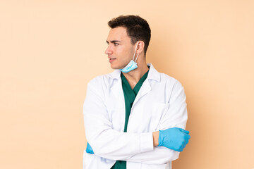 Young dentist man holding tools isolated on beige background portrait