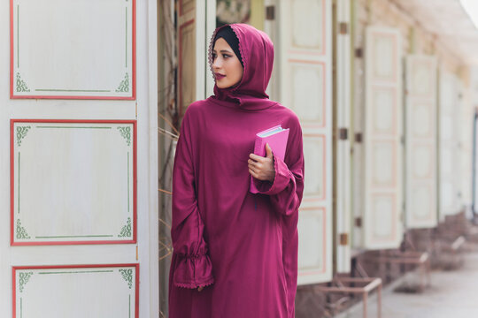 Confident Arab businessman smiling and walks of Dubai. Arab Business vumen hijab is in the streets against the skyscrapers of Dubai. The woman is dressed in a black abaya.