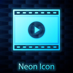 Glowing neon Online play video icon isolated on brick wall background. Film strip with play sign. Vector