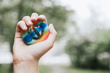 colorful trendy antistress sensory fidget push toy Snapperz in kid's hands on background of sky and trees - obrazy, fototapety, plakaty
