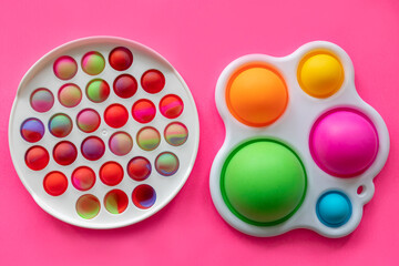 colorful antistress sensory toys fidget push pop it on pink background