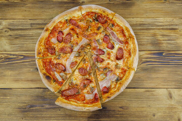 Delicious fresh pizza with sausage, mushrooms and cheese on a wooden table. Top view