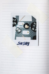 Notebook page with taped instax photo of  sushi on the table