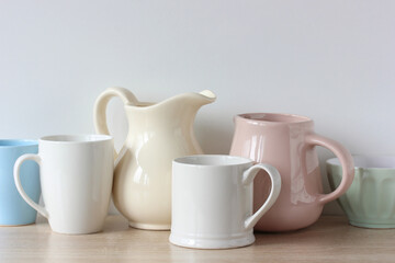 Fototapeta na wymiar light-colored jugs and mugs on the shelf.