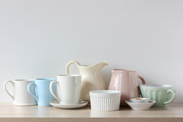 light-colored jugs and mugs on the shelf, kitchen background.