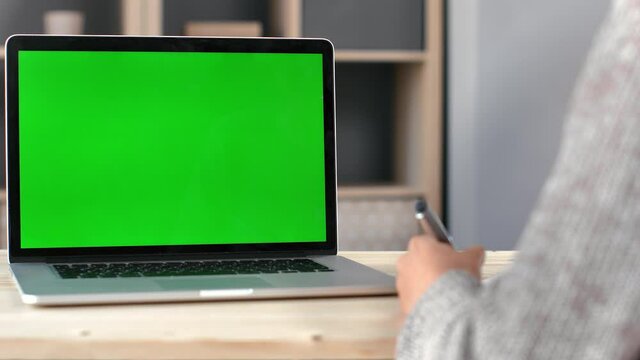 Closeup female hands writing making notes on paper with pen in front of green screen desk chroma key