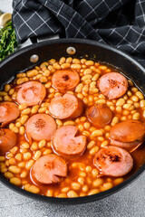 Stewed beans with smoked sausage and tomato sauce in a pan. White background. Top view