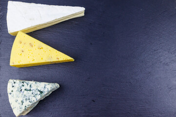 Set of various types of cheese on black slate background. Top view