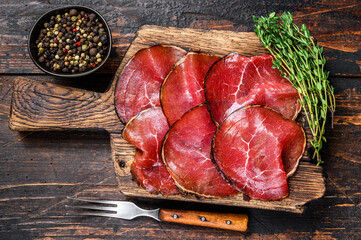 Italian Antipasti Bresaola cured meat beef cut pieces. Dark wooden background. Top view