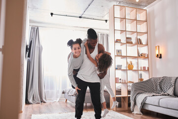 Father with little kids standing in living room and having fun together
