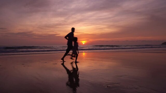 Daughter holding hands of dad on the beach running on sandy shore at sunset Amazing light sunset or sunrise sky watching sea Happiness travel and bliss concept video