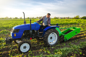 A farmer on a tractor digs potatoes with a digger. The use of modern technology on the farm. Free...
