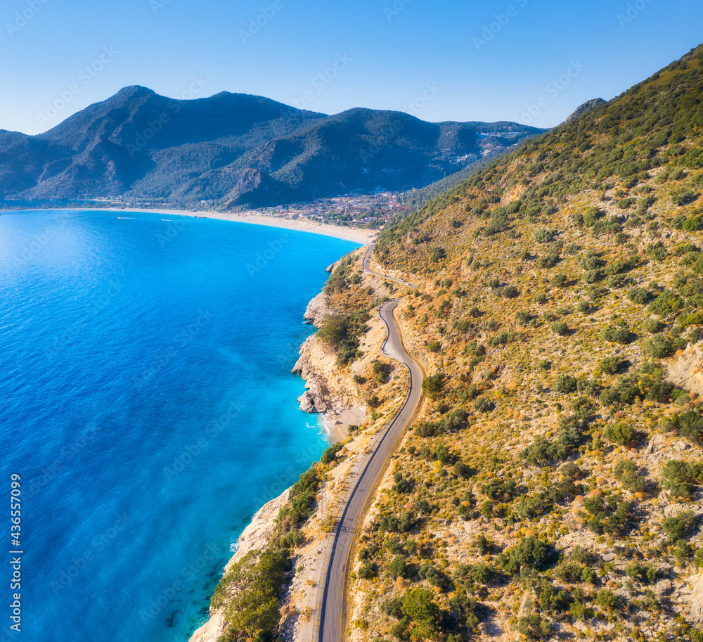 Wall mural Aerial view of mountain road near blue sea, sandy beach at sunset in summer. Oludeniz, Turkey. Top view of road, trees, clear water, mountain. Beautiful landscape with highway, rocks and sea coast	 - Wall murals