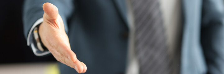 Man in business suit giving his hand for handshake closeup