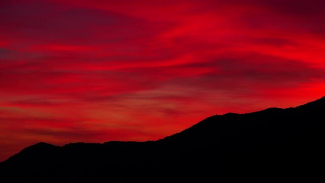Skyscape. Red sky with clouds at sunset over hills. Evening nature landscape.