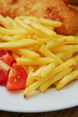 Traditional english dish with battered white cod, french fries and fresh vegetable served on a white plate. Close up. Vertical image