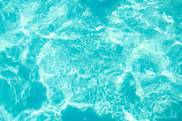 Fototapeta na wymiar Light blue pool water with sun glare abstract blurred background