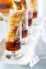 A row of french toast finger food appetizers in shot glasses with maple syrup.