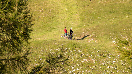 Two females on mountain bikes talking and looking at beautiful green nature.