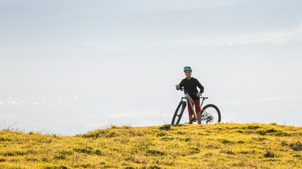 Obraz premium Girl child riding mountain bike at sunset. Beautiful golden summer light.