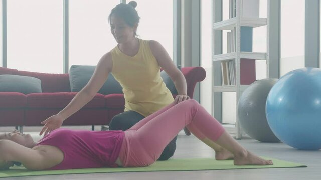 Coach training young asian woman sit-ups exercise for body weight with strong together at gym, female workout with sit up for abdominal muscle, instructor support and assistant workout for health.