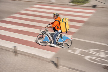 Fototapeta na wymiar Man wearing protective mask riding at the bicycle while making food delivery