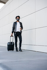 Tourist man carrying suitcase while walking outdoors.