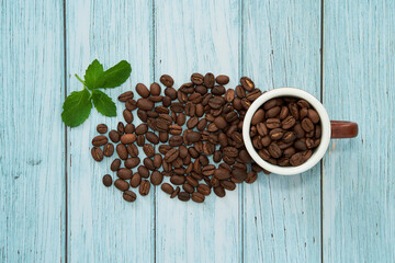 Top view of a cup with coffee beans. Delicious espresso beans surrounded.