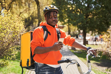 Naklejka premium Delivery man using smartphone at the street before the delivering order