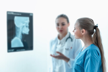 Female Orthopedics Physician Doctor is Examining Patient X-Ray Film in Examination Room While Consulting Health Problem. Orthopedic Doctor is Explaining Medic Surgery Solution Treatment to Her Patient