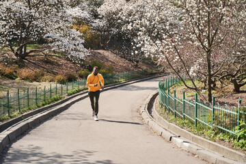 Young man jogging in spring park in morning