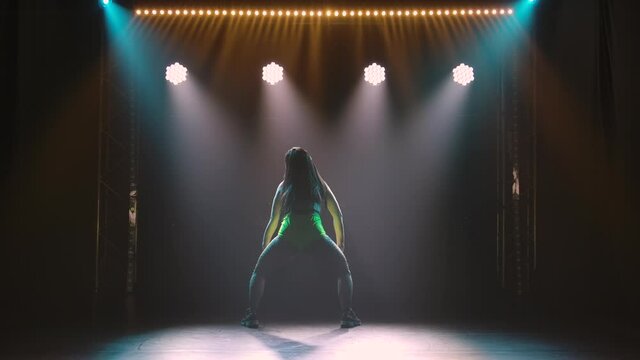 Female dancer shakes ass dancing twerk. Beautiful women dancing booty dance. Silhouette of a slender body in the colored beams of spotlights. Slow motion.
