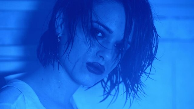 depressed young woman stares at the camera in the ultraviolet light