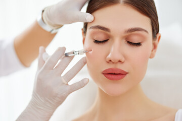 Cosmetician applying filler injection to patient