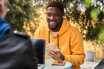 Fototapeta premium Man chatting during coffee break with his friend and eating sandwich