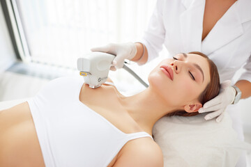 Obraz na płótnie Canvas Cosmetologist treating neck, decollete area and chest of woman with laser machine