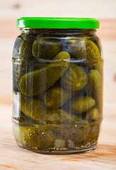 Glass jar with pickled cucumbers on a wooden table. High quality photo