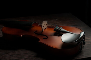 Side view of a Violin on a rustic table in low key light or dark photography with a black background