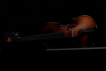 Abstract image of a Violin and violin bow in low-key light photography in a black background, baroque or renaissance style.