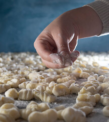 Manos de mujer arrojan harina sobre la pasta. Concepto de comida elaborada en casa. Ñoquis de papa. 