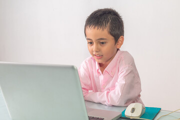 .A boy wearing a pink shirt was enjoying watching the laptop happily..Studio portrait, concept with white background.
