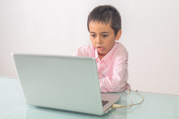 .A boy wearing a pink shirt was enjoying watching the laptop happily..Studio portrait, concept with white background.