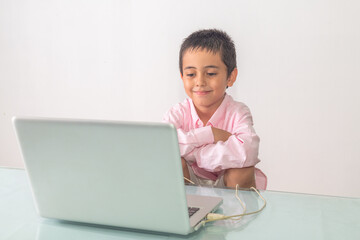 .A boy wearing a pink shirt was enjoying watching the laptop happily..Studio portrait, concept with white background.