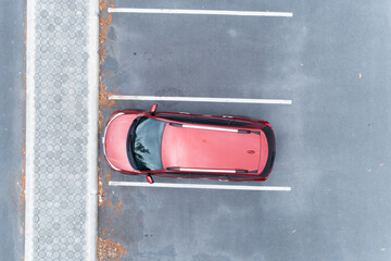 Aerial view top down of red SUV car parked at concrete car parking lot with white line of traffic...