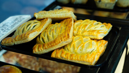 Freshly made empanadas with cheese and spinach displayed for sale, price tag with description on...