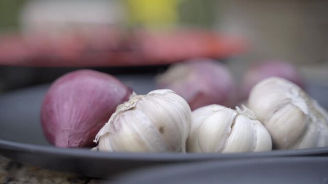 hand-held, selective focus pan across plates of chilies, onions, garlic