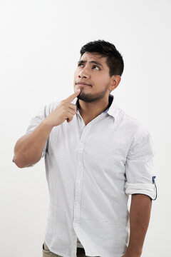 Hombre latino pensando mientras mira hacia arriba con su dedo en el ment&oacute;n
