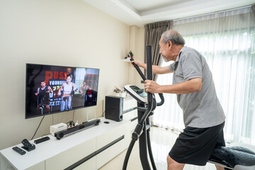 Senior old man use exercise bike machine, follow workout video at home